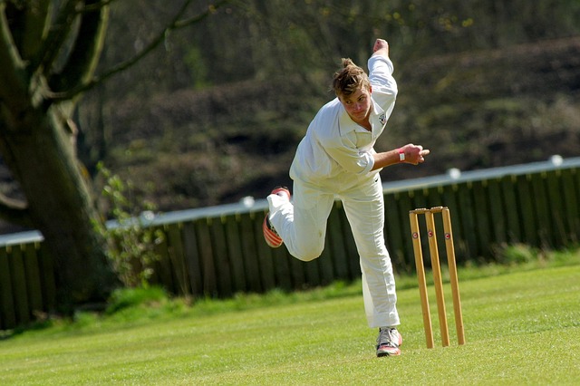 Cricket coach demonstrating a bowling action to a young, attentive player.