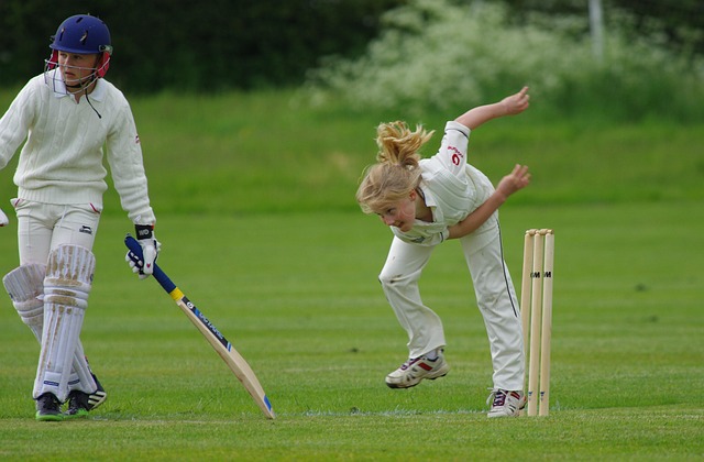 Cricketer preparing for a powerful shot, focusing intently on the ball.